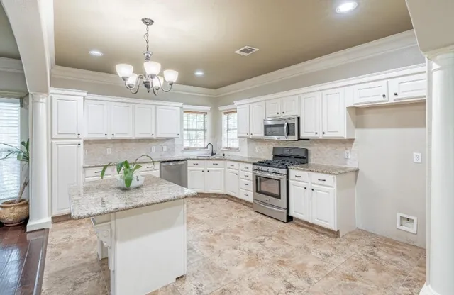 a kitchen with stainless steel appliances granite countertop a refrigerator a stove a sink dishwasher and white cabinets with wooden floor