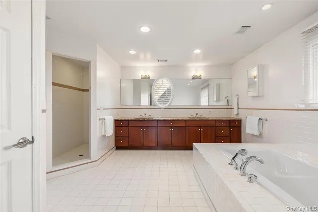 a large bathroom with a tub a sink shower and mirror