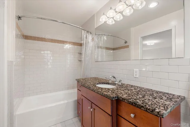 a bathroom with a granite countertop sink a mirror and a bathtub