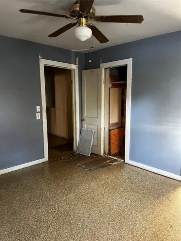 an empty room with closet and a chandelier fan