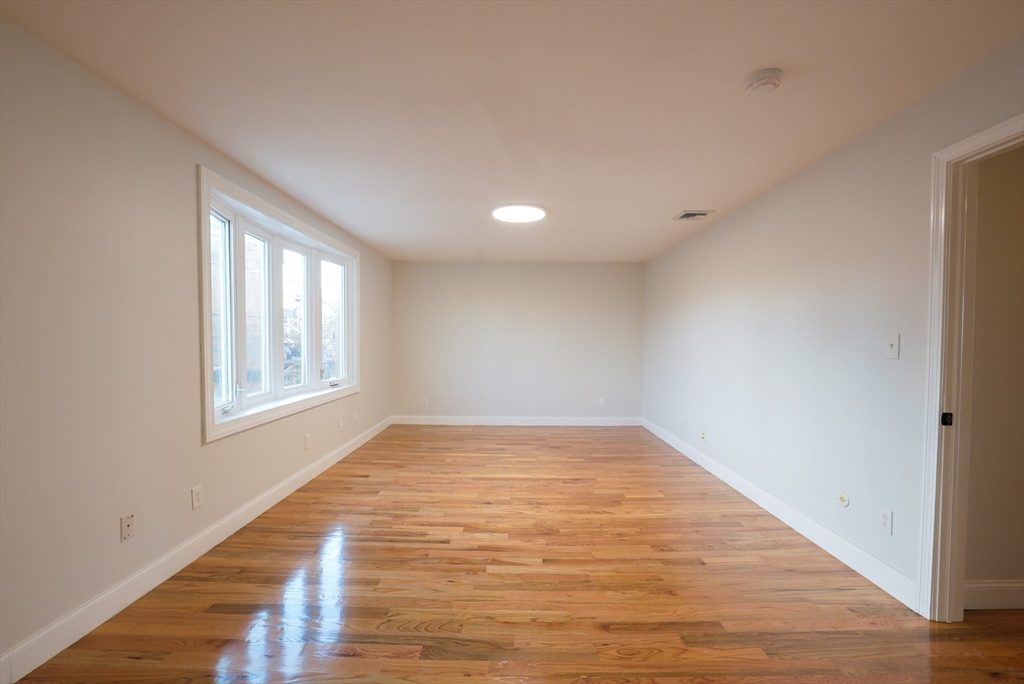 262 East Eagle Street, Unit 2 Boston, MA 02128 - Photo 6 of 24 a view of an empty room with wooden floor and a window