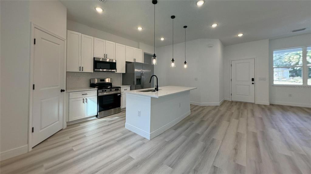 2018 West Magenta Drive Citrus Springs, FL 34434 - Photo 4 of 19 a large kitchen with stainless steel appliances granite countertop a large center island a sink dishwasher a refrigerator and white cabinets with wooden floor