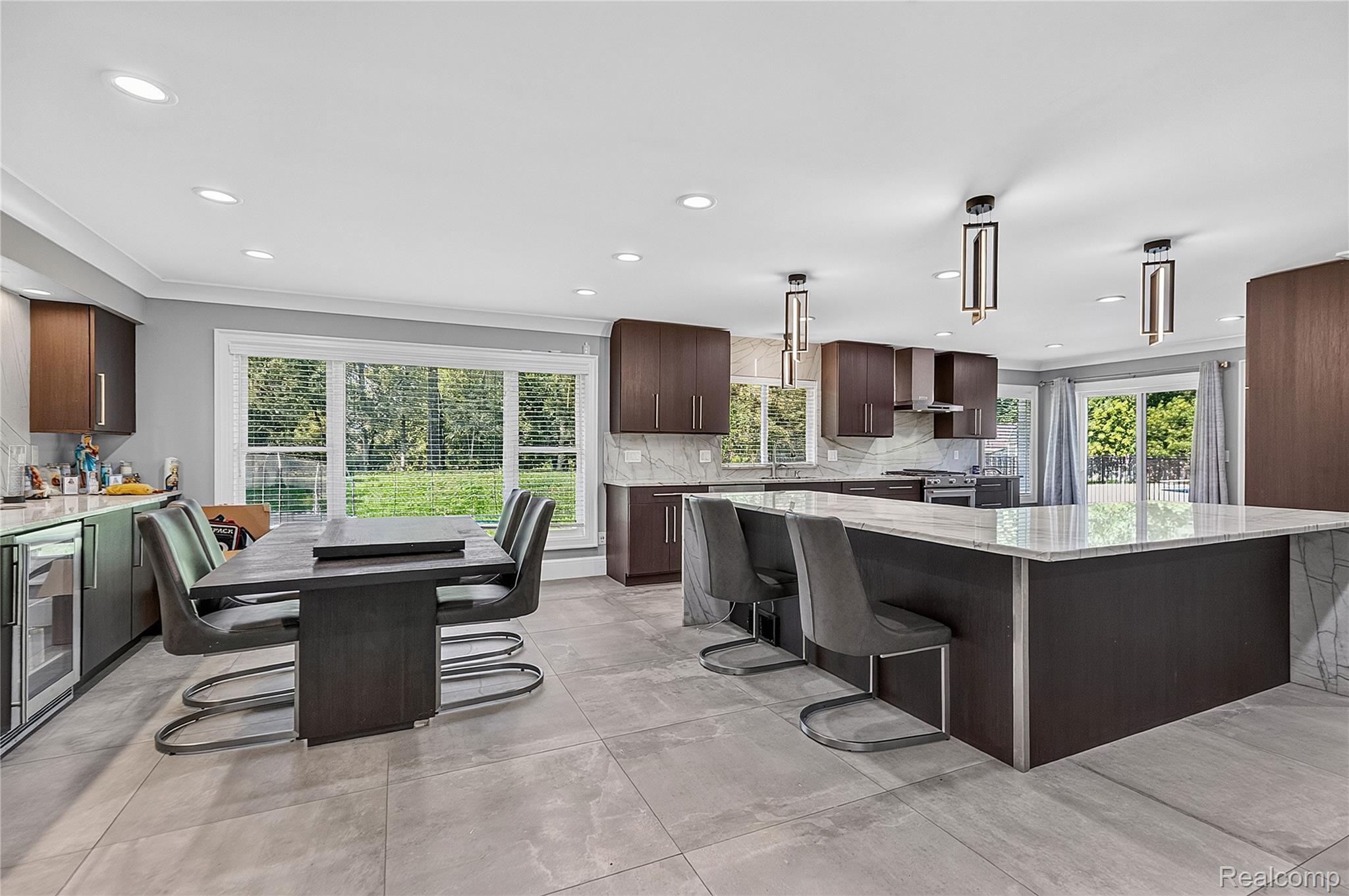 15879 Millar Road Clinton Township, MI 48036 - Photo 12 of 65 Modern kitchen with a large central island, dark wood-finish cabinetry, light-toned tile flooring, and integrated recessed lighting