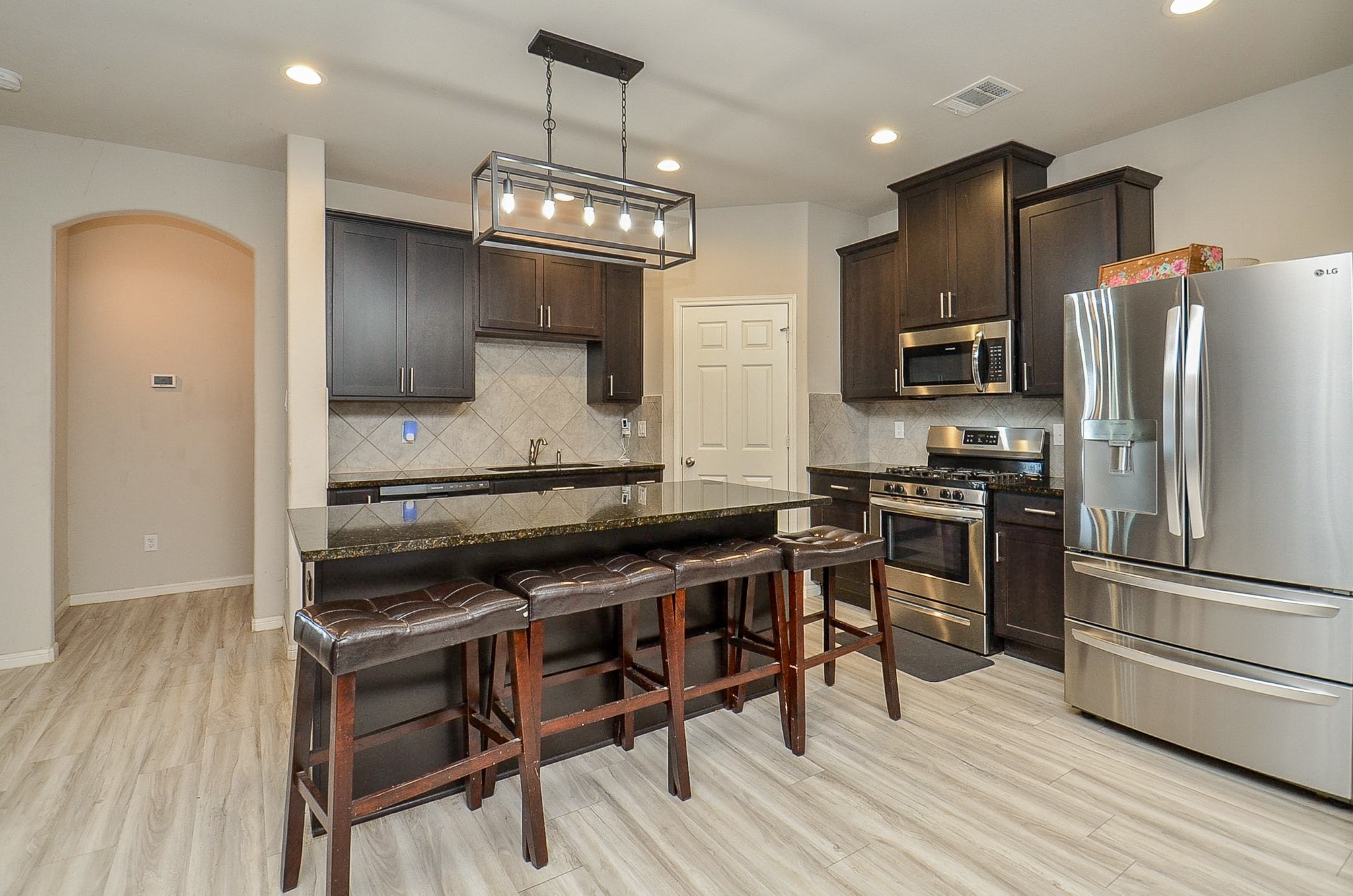 10519 Scrub Oak Drive Rosharon, TX 77583 - Photo 14 of 32 a kitchen with stainless steel appliances a stove a refrigerator and a wooden floor