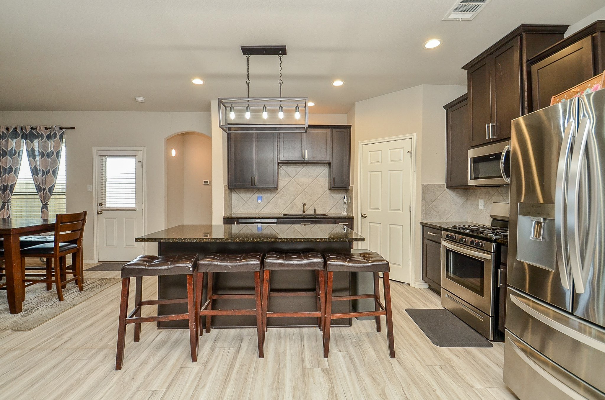 10519 Scrub Oak Drive Rosharon, TX 77583 - Photo 15 of 32 a kitchen with stainless steel appliances a dining table chairs stove refrigerator and cabinets