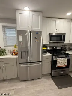 a kitchen with stainless steel appliances granite countertop a refrigerator a stove a sink and a microwave