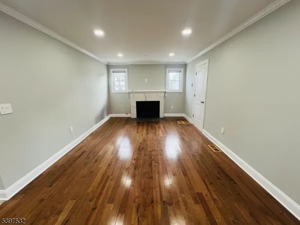 an empty room with wooden floor fireplace and windows