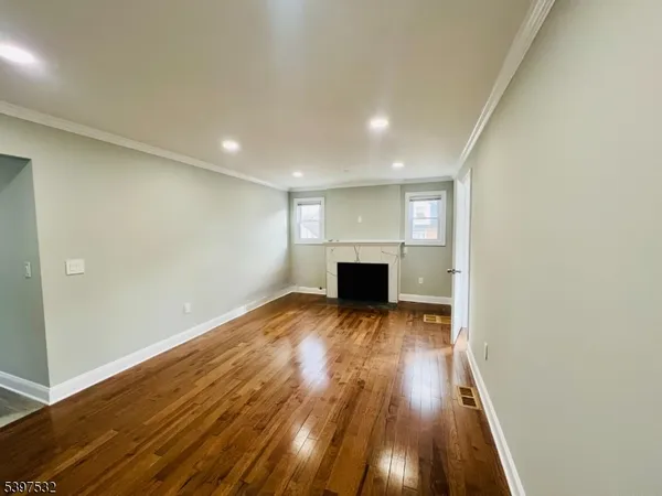 a view of empty room with wooden floor and fireplace