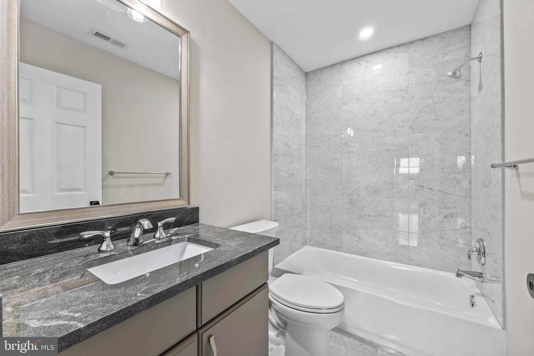 5393 Merry Oaks Road The Plains, VA 20198 - Photo 32 of 58 a bathroom with a granite countertop sink toilet mirror and bathtub