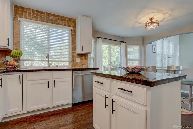 a kitchen with granite countertop white cabinets and a large window