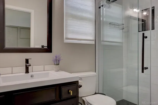 a bathroom with a sink a toilet a mirror and shower