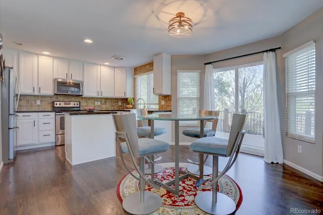 a kitchen with a dining table chairs and white cabinets