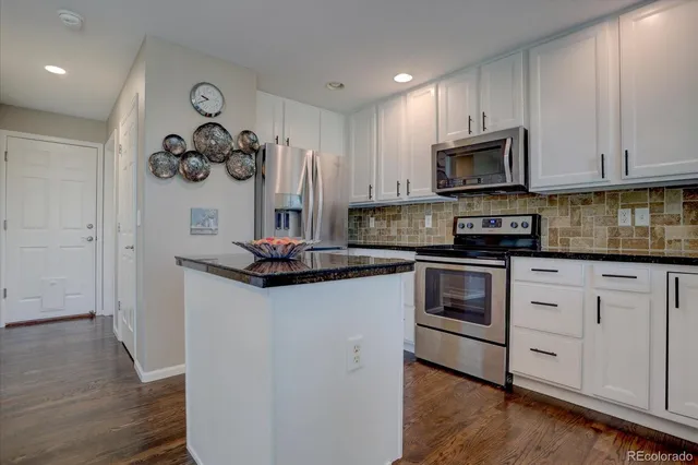 a kitchen with stainless steel appliances granite countertop a refrigerator and a stove top oven