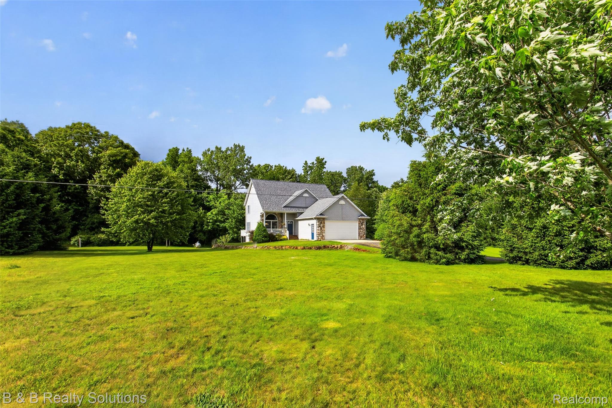 3097 East Burnside Road North Branch, MI 48461 - Photo 3 of 52 Spacious green lawn surrounding a residence with white siding, a gray shingle roof, and a stone-accented garage