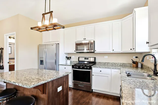 a kitchen with stainless steel appliances granite countertop a sink stove refrigerator and cabinets