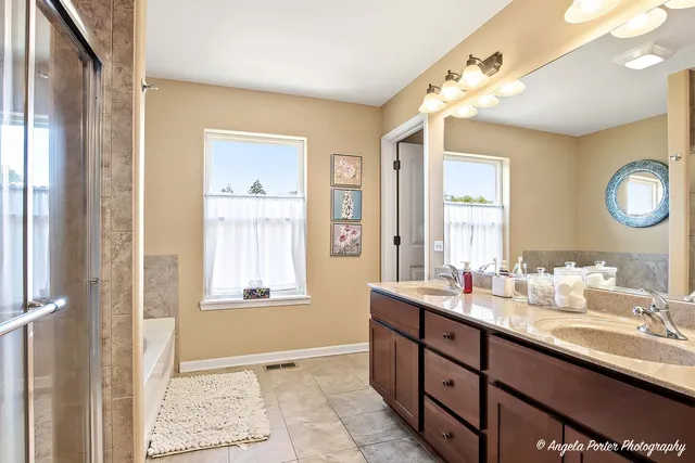 a bathroom with a double vanity sink a mirror and a bathtub