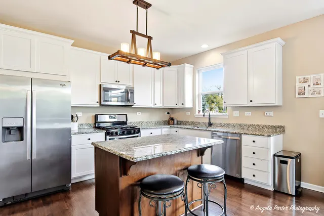 a kitchen with stainless steel appliances granite countertop a sink a stove a refrigerator and cabinets