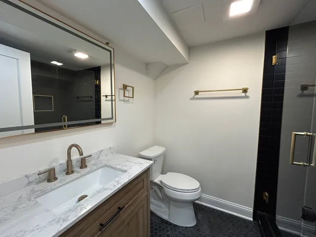 a bathroom with a toilet a sink a mirror and vanity