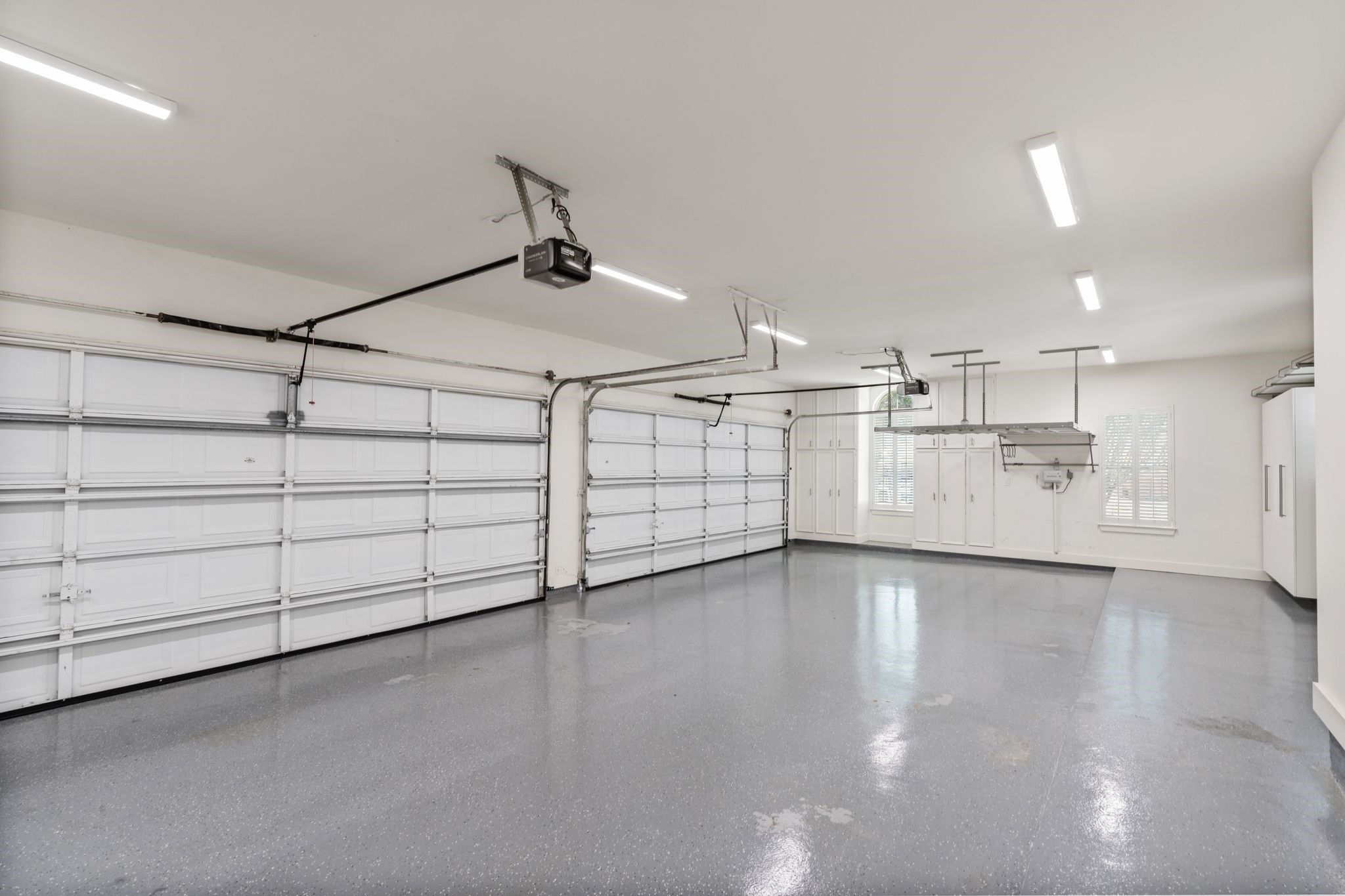 31 Hollymead Drive Spring, TX 77381 - Photo 48 of 50 Spacious and well-lit 4-car garage with durable epoxy flooring, custom storage cabinets, and modern overhead doors with openers. Perfect for vehicle storage and workshop space.