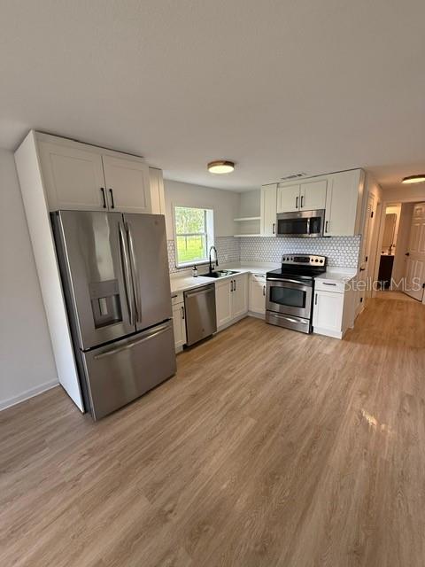 2312 Southwest Fort King Street Ocala, FL 34471 - Photo 5 of 17 a kitchen with stainless steel appliances a refrigerator a stove a sink cabinets and a wooden floor