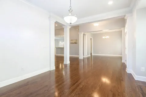 an empty room with wooden floor chandelier and windows