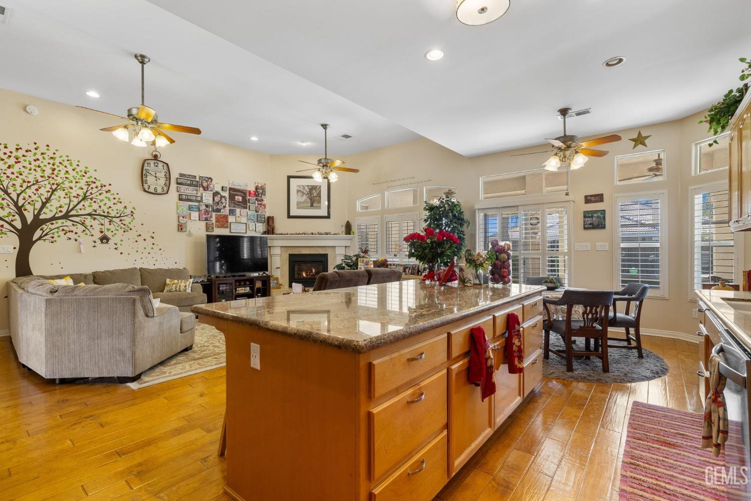 Undisclosed Address Bakersfield, CA 93313 - Photo 15 of 49 an open kitchen with granite countertop a stove a sink a dining table and chairs with wooden floor
