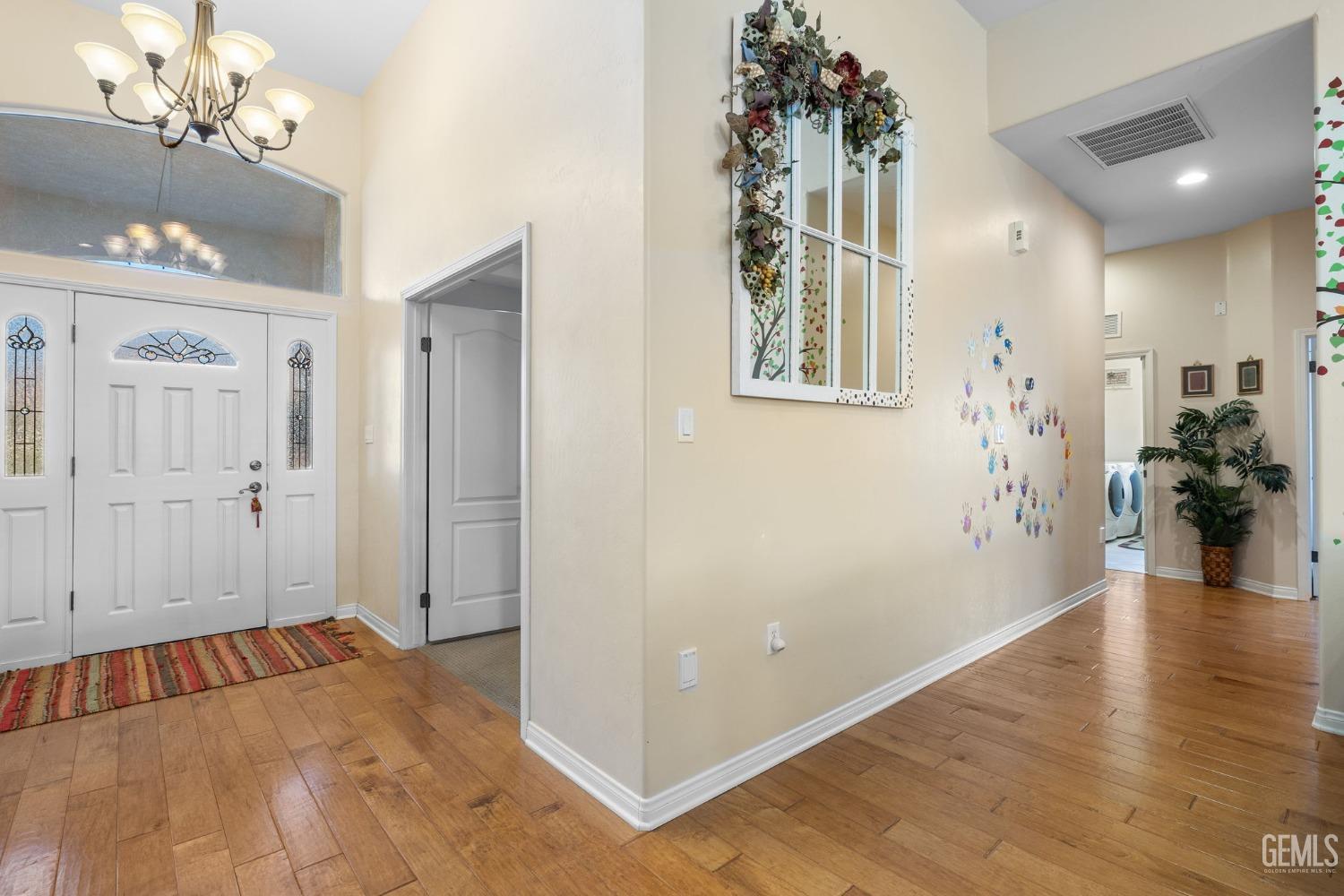 Undisclosed Address Bakersfield, CA 93313 - Photo 23 of 49 a view of livingroom with a hallway view with wooden floor and a chandelier