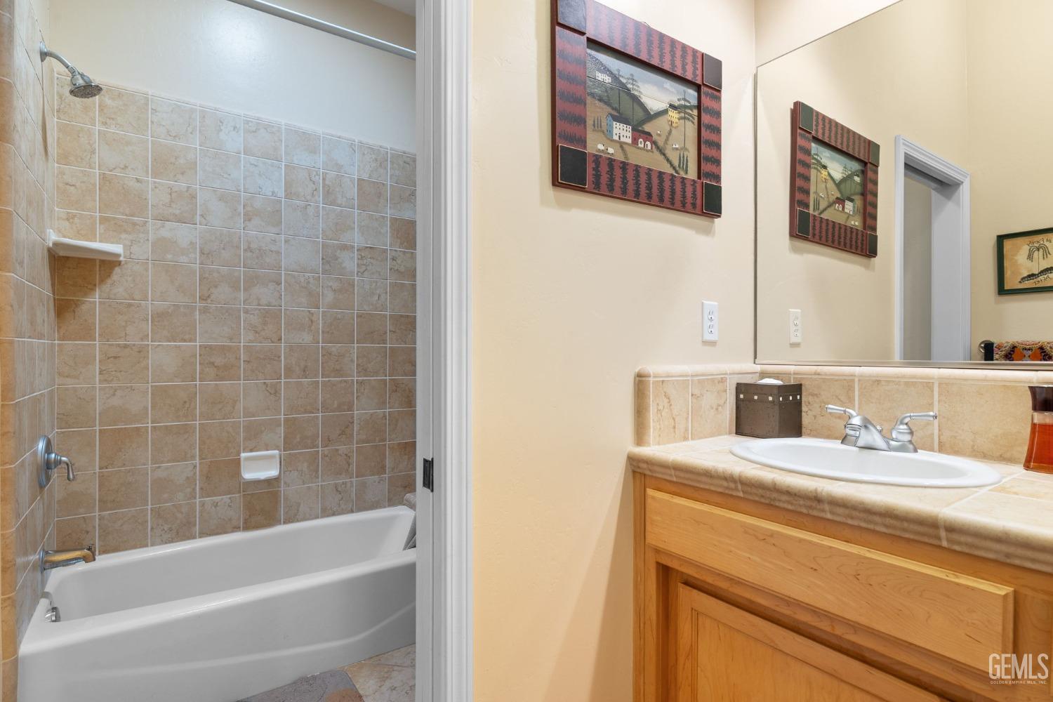 Undisclosed Address Bakersfield, CA 93313 - Photo 36 of 49 a bathroom with a granite countertop sink a mirror a bathtub and shower
