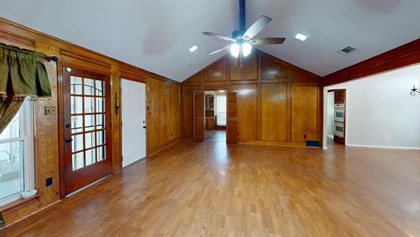 a view of an empty room with wooden floor and a window
