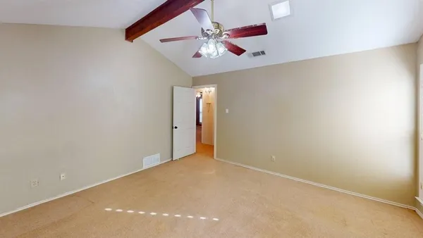 an empty room with a chandelier fan and windows