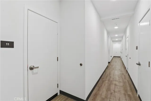 a view of a hallway with wooden floor and a bathroom