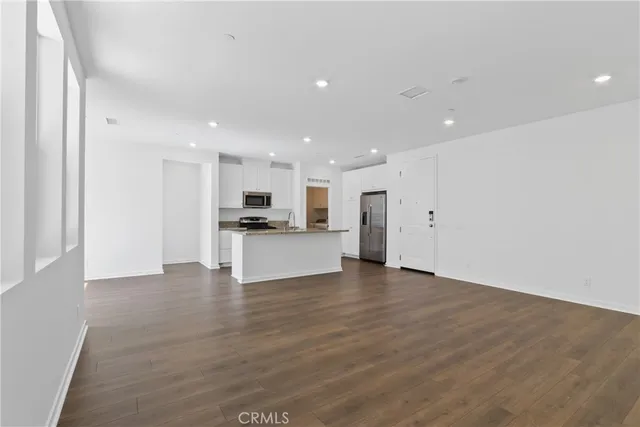 a view of kitchen with kitchen island refrigerator sink and white cabinets with wooden floor