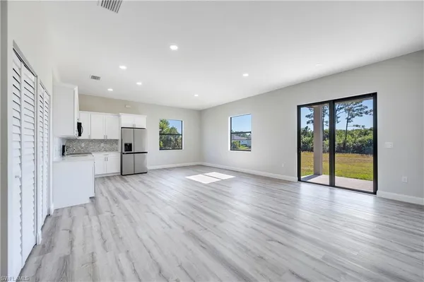 a view of an empty room with window and wooden floor