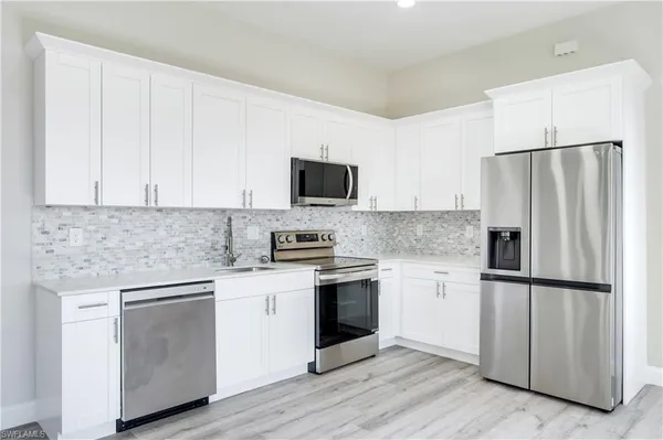 a kitchen with white cabinets and stainless steel appliances