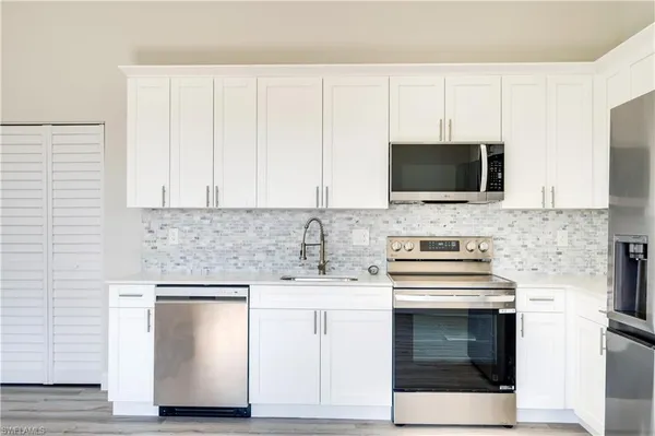 a kitchen with white cabinets stainless steel appliances and sink