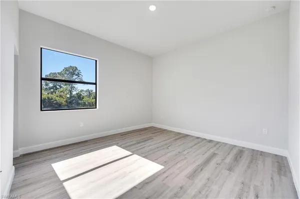 an empty room with wooden floor and window