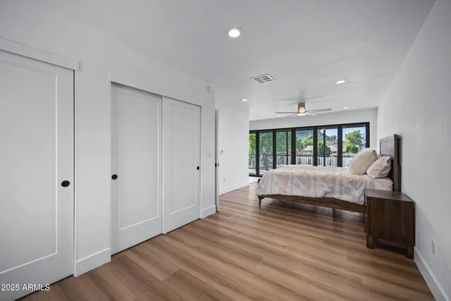 a spacious bedroom with a bed and wooden floor