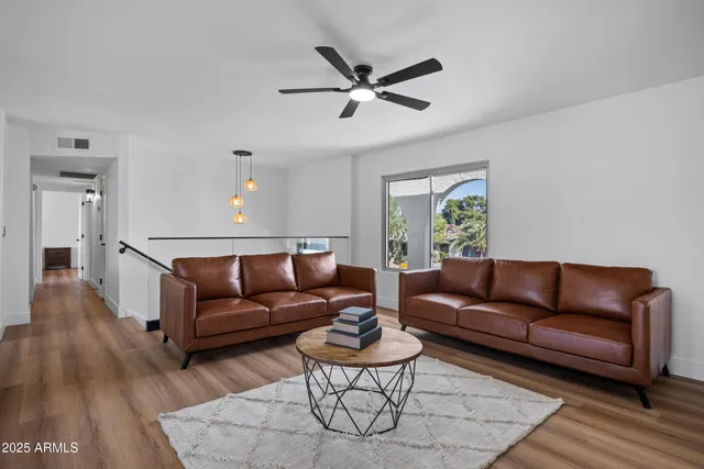 a living room with furniture a bed and a ceiling fan