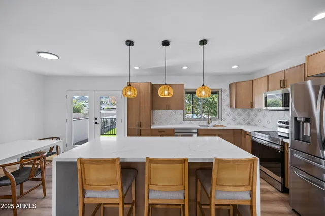 a kitchen with stainless steel appliances kitchen island granite countertop a table chairs and a refrigerator