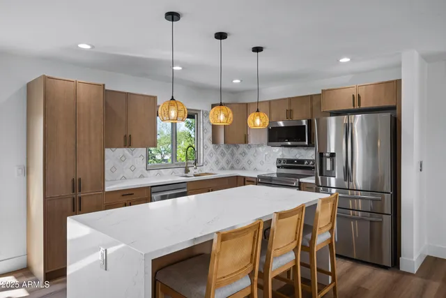 a kitchen with stainless steel appliances a refrigerator a sink a stove a dining table and chairs