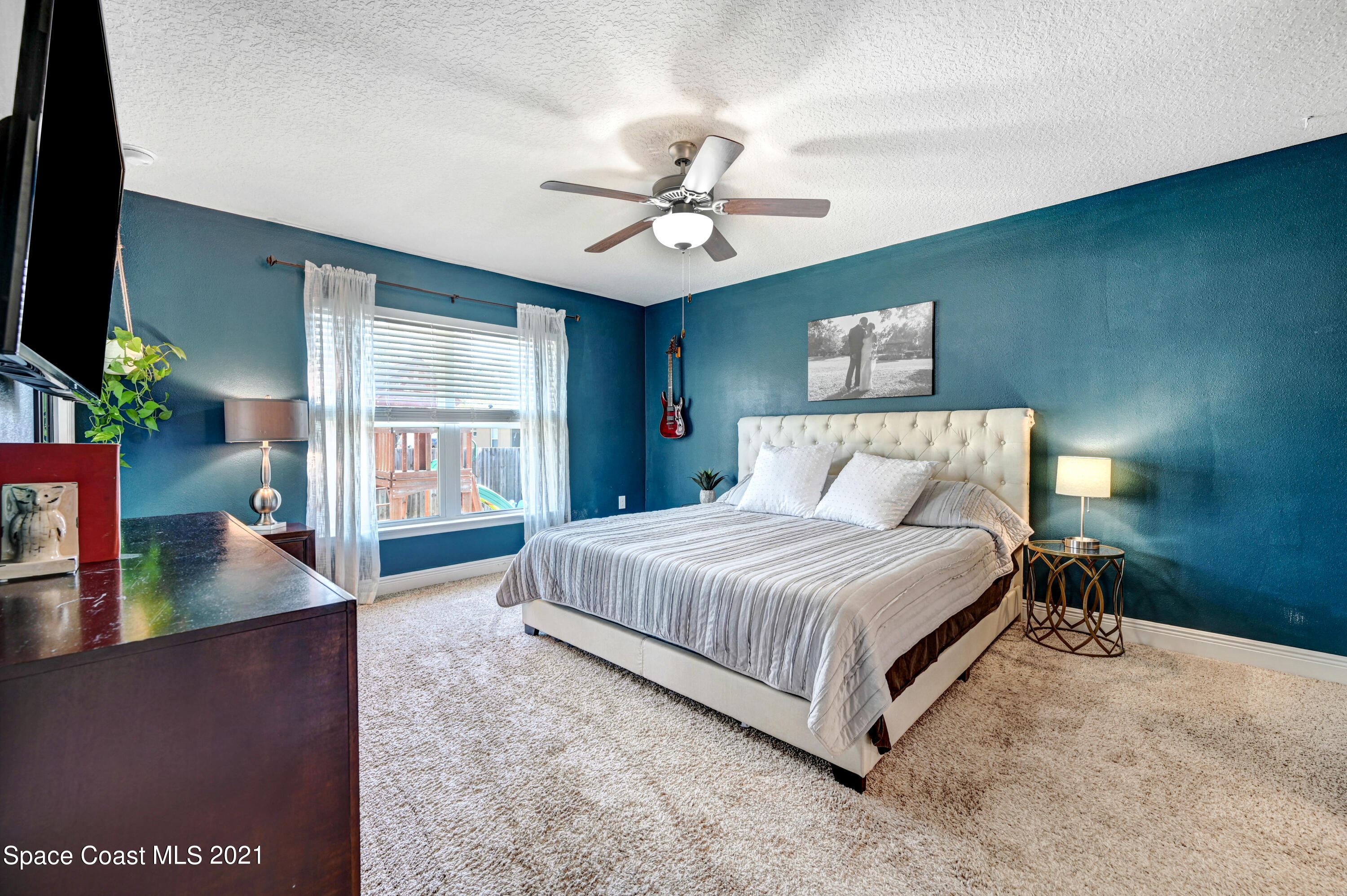 737 Atlantis Road Southeast Palm Bay, FL 32909 - Photo 12 of 29 a spacious bedroom with a bed and a flat tv screen on dresser