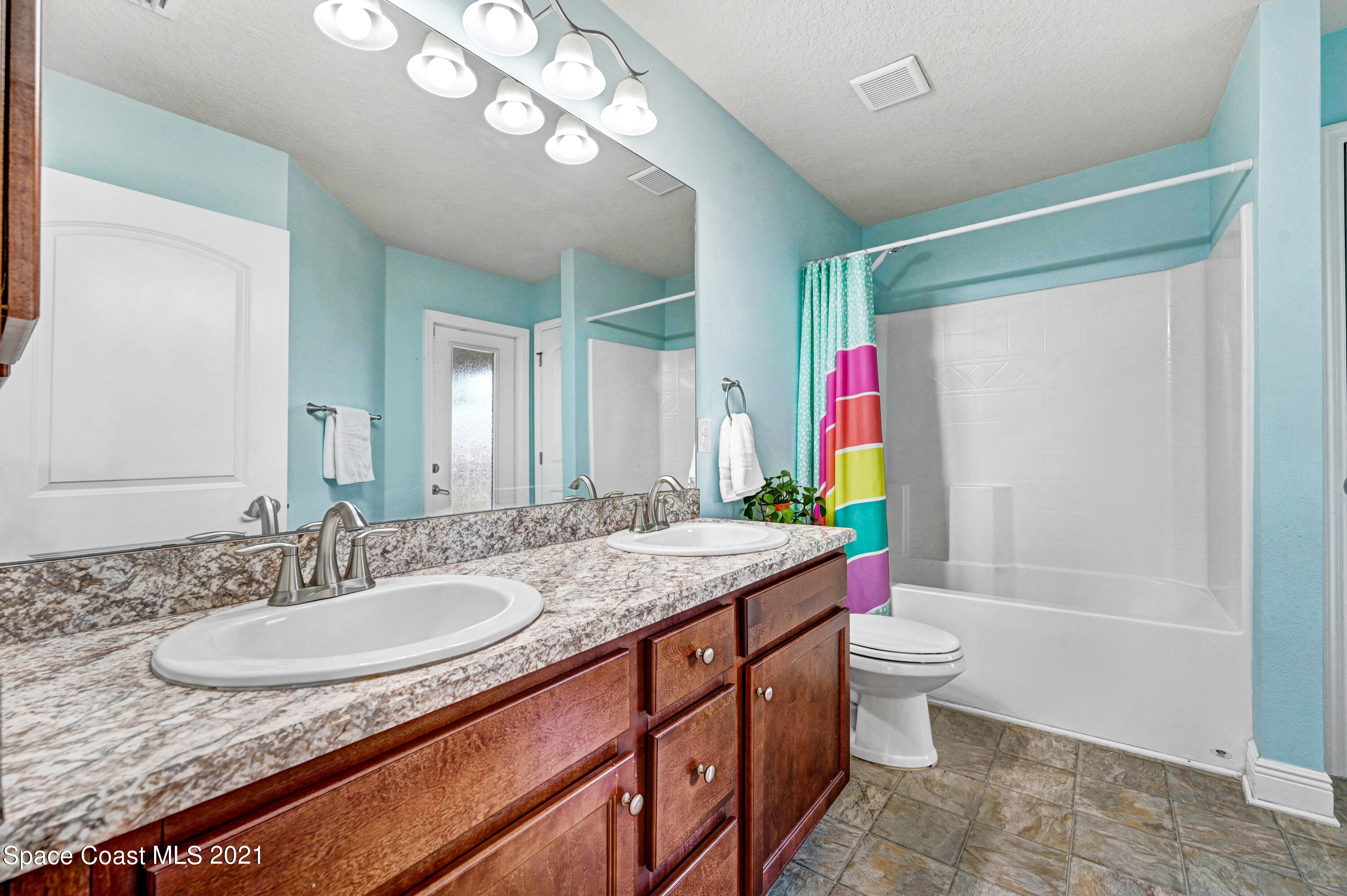 737 Atlantis Road Southeast Palm Bay, FL 32909 - Photo 21 of 29 a bathroom with a granite countertop sink a toilet a mirror a vanity and bathtub