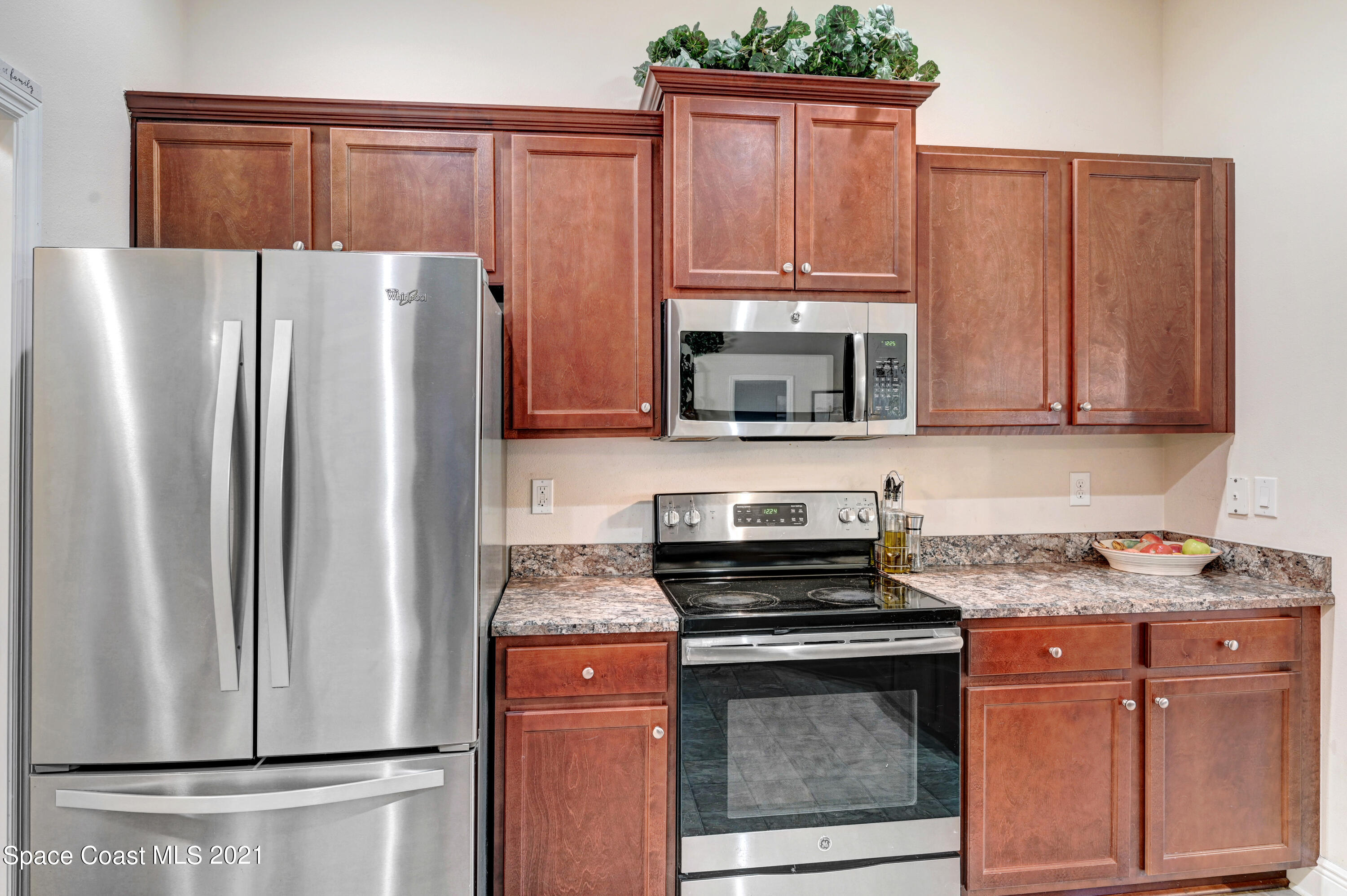 737 Atlantis Road Southeast Palm Bay, FL 32909 - Photo 8 of 29 a kitchen with granite countertop a refrigerator stove and microwave