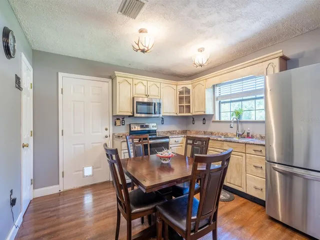 a kitchen with stainless steel appliances granite countertop a dining table chairs refrigerator and cabinets