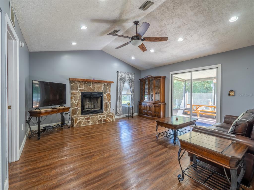 13425 Maple Drive Fort McCoy, FL 32134 - Photo 10 of 41 a living room with furniture a fireplace and a flat screen tv