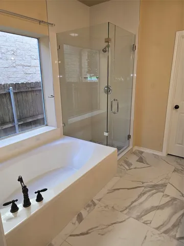 a bathroom with a tub shower sink and mirror