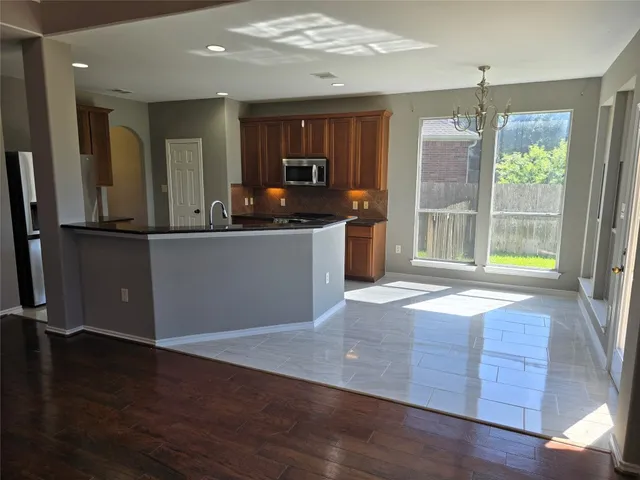 a kitchen with stainless steel appliances granite countertop a refrigerator a stove and a wooden floors