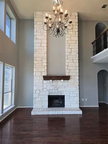 a view of a livingroom with a fireplace a chandelier and wooden floor