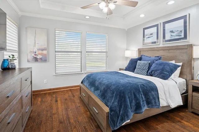 a bedroom with a bed and dresser with wooden floor