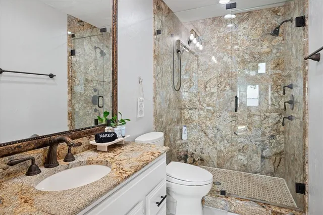 a bathroom with a granite countertop sink toilet and shower